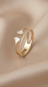 Anillo doble de acero con baño de oro, compuesto por una banda con circonias engastadas y otra banda abierta con extremos decorados con nácar en forma de gota.