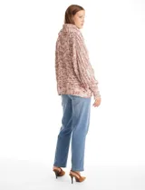 Buzo tejido en punto aran con cuello volcado y mangas largas con puño. Presenta un diseño jaspeado en tonos rosados y beige.