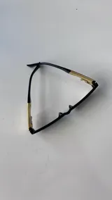 Lentes de sol rectangulares con marco negro y patillas con detalle metálico dorado en forma de greca.