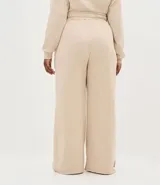 Pantalón de corte wide leg en color beige, con cintura elástica, bolsillos laterales y abertura en el ruedo. Confeccionado en tejido de algodón y poliéster con caída amplia.