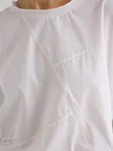 Remera de silueta relajada con cortes geométricos en el frente y costuras a la vista en tono contrastante. Presenta cuello redondo y mangas largas.