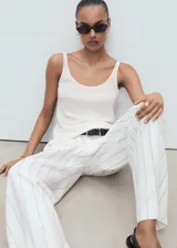Top de lino color blanco, sin mangas, con cuello redondo y tirantes anchos de corte recto.
