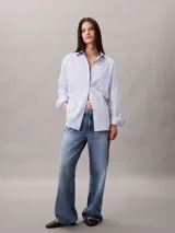 Camisa de popelina de algodón de corte relaxed, color celeste, con cuello clásico, cierre frontal con botones y bolsillo en el pecho con monograma CK bordado.