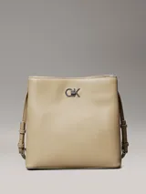 Cartera tipo saco de piel sintética estructurada color beige, con correa ajustable para el hombro y herrajes plateados. Presenta el monograma de Calvin Klein en la parte frontal.