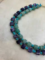 Collar de cuentas de piedra natural en tonos verde y lila, intercaladas con cuentas turquesas y detalles dorados.
