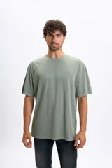 Remera oversize de manga corta color verde, con estampado frontal de texto en tono más claro.