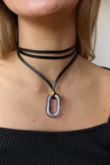 Gargantilla de tiento de cuero negro con dije colgante de piedra natural ovalada y medalla metálica dorada grabada.