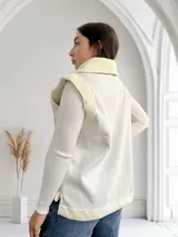 Chaleco blanco con cierre frontal, cuello y bolsillos con textura de piel sintética.