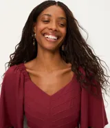 Vestido midi color bordó, con escote en V, mangas cortas evasé y falda en capas con recorte tipo María. La parte trasera tiene elástico para un mejor ajuste. Confeccionado en viscosa certificada y poliamida.