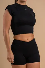 Conjunto deportivo color crema compuesto por un top corto de mangas cortas y unos shorts de tiro alto.