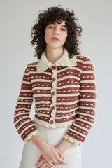 Saco tejido de lana con diseño a rayas horizontales en color marrón y crema. Presenta cuello tipo bebé, cierre frontal con botones forrados en lana y terminaciones con borde festoneado en puños y ruedo.