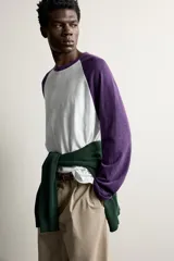 Remera manga larga de corte regular fit, con diseño estilo raglán en color blanco y mangas en color violeta oscuro.