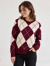 Sweater de tejido de punto con diseño de rombos en color bordó y crema. Presenta cuello redondo, mangas largas y puños y ruedo acanalados.