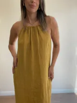 Vestido largo de lino color negro oscuro, con escote fruncido y tirantes finos ajustables. Presenta aberturas laterales en el ruedo.