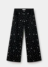Jeans rectos de tiro medio en tejido de algodón vaquero color negro, con diseño de cinco bolsillos, trabillas para cinturón y cierre frontal con botón y cremallera. Presenta aplicaciones de tachuelas brillantes a lo largo de las piernas.