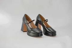 Zapatos de cuero negro con plataforma y taco cuadrado. Presentan una tira delgada sobre el empeine con hebilla dorada.