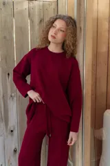Conjunto de dos piezas color tostado, compuesto por un buzo de cuello redondo con mangas largas y hombros caídos, y un pantalón de corte recto con cintura elástica y cordón ajustable.