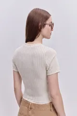 Top de manga corta color beige, confeccionado en tejido elastizado con textura acanalada, cuello redondo y calce al cuerpo.