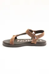 Sandalias planas de cuero marrón con tiras regulables mediante velcro y suela negra.