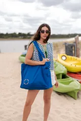 Bolso tipo tote bag azul con asas al hombro.