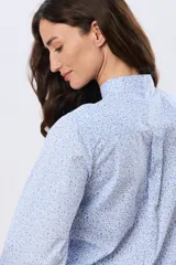 Camisa de algodón celeste con estampado floral pequeño, cuello mao, mangas largas con puños fruncidos y cierre frontal de botones.