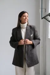 Blazer de corte sastrero en color gris oscuro con textura jaspeada. Presenta solapas clásicas, cierre frontal de doble botonadura y un bolsillo superior con detalle de pañuelo decorativo.