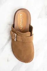 Zueco de cuero color marrón claro, con hebilla metálica plateada ajustable y suela plana con ranuras.