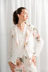 Blazer de lino con estampado floral en tonos rosados y verdes, cuello con solapa, bolsillos laterales y cierre frontal con un botón.