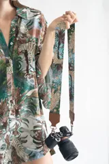 Correa para cámara con estampado de tigres, palmeras y estrellas sobre fondo azul y verde.