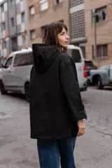 Parka liviana color beige con capucha, cierre frontal con botones, bolsillos delanteros con tapa y ajuste en la cintura. Presenta mangas con puños vueltos y detalle de botones.