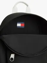 Mochila compacta Tommy Jeans color negro, con diseño curvo, compartimento principal con cierre de cremallera, bolsillo exterior con cremallera y parche con el logo de la marca en la parte delantera. Cuenta con correas ajustables y acolchadas.