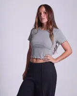 Remera de morley de algodón, color gris, con cuello redondo, manga corta y terminaciones con borde fruncido.