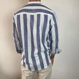 Camisa celeste y blanca a rayas verticales, de lino, con cuello mao y mangas largas con puños.