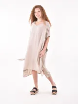 Vestido de tela fluida color marrón medio, con escote en V y mangas cortas tipo kimono. El ruedo es asimétrico con aberturas laterales.