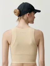 Top deportivo color beige, de cuello redondo con cierre frontal parcial y diseño ajustado.