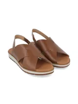 Sandalia de cuero color camel con tiras cruzadas en el empeine, tira trasera de ajuste y suela plana con plataforma dentada en tono blanco y marrón.
