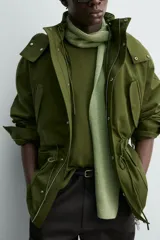 Parka técnica color verde militar de corte relaxed fit con cuello subido y capucha desmontable. Cuenta con bolsillos con solapa en el pecho y en la cadera, cintura ajustable con cordón y cierre frontal de cremallera oculta por solapa con botones a presión. Incluye un chaleco interior desmontable acolchado.
