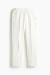 Pantalón tipo jogger de punto en color blanco, con pliegue cosido frontal, cintura elástica con cordón ajustable, bolsillos laterales y un bolsillo insertado trasero. Corte regular.