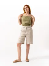 Bermuda beige de lino con corte sastrero, tiro alto, pinzas delanteras, cierre con botón y presillas para cinturón.