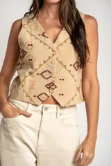 Chaleco de algodón color beige con estampado geométrico en tonos bordó y marrón. Presenta escote en V, cierre frontal con botones y corte recto.