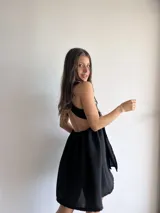 Vestido corto negro con escote halter y espalda descubierta. Presenta un corte a la cintura con falda acampanada.