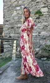 Vestido midi de seda con estampado estilo boho, escote en V, mangas 3/4 con volados y detalle de franja central contrastante. Presenta una cintura elástica y ruedo con volado.