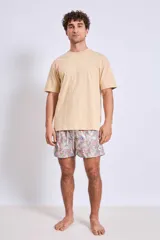 Short de baño con estampado botánico en tonos tierra, rosados y verdes. Presenta cintura elástica con cordón ajustable y un pequeño parche con logo en el ruedo.