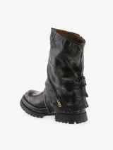 Bota corta de cuero bovino con efecto desgastado en tonos negro y gris. Presenta un diseño robusto con caña arrugada y una cremallera diagonal decorativa con tirador dorado. La suela es gruesa y dentada.