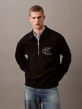Sweater negro de Calvin Klein con cuello tipo chomba, cierre de cremallera parcial y logo "CK" bordado en blanco en el pecho.