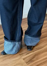 Pantalon de jean azul oscuro con costuras en contraste, corte wide leg y ruedo con doblez ancho en tono denim claro.