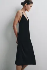 Vestido midi de color negro, con escote en pico y tirantes finos cruzados en la espalda.