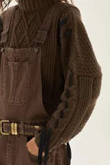 Polera de tejido de punto con diseño de ochos y detalles de tientos en contratono en las mangas. Presenta cuello alto y corte cropped.