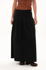 Pollera larga de color negro con corte a la cadera y detalle de frunce que aporta volumen y movimiento a la prenda. Confeccionada en tela suave con acabado tipo piel de durazno.