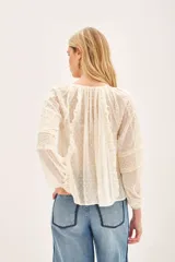 Camisa de manga larga confeccionada en tela plumeti, con cuello redondo, tajo delantero con cordones ajustables y volados verticales en el frente.